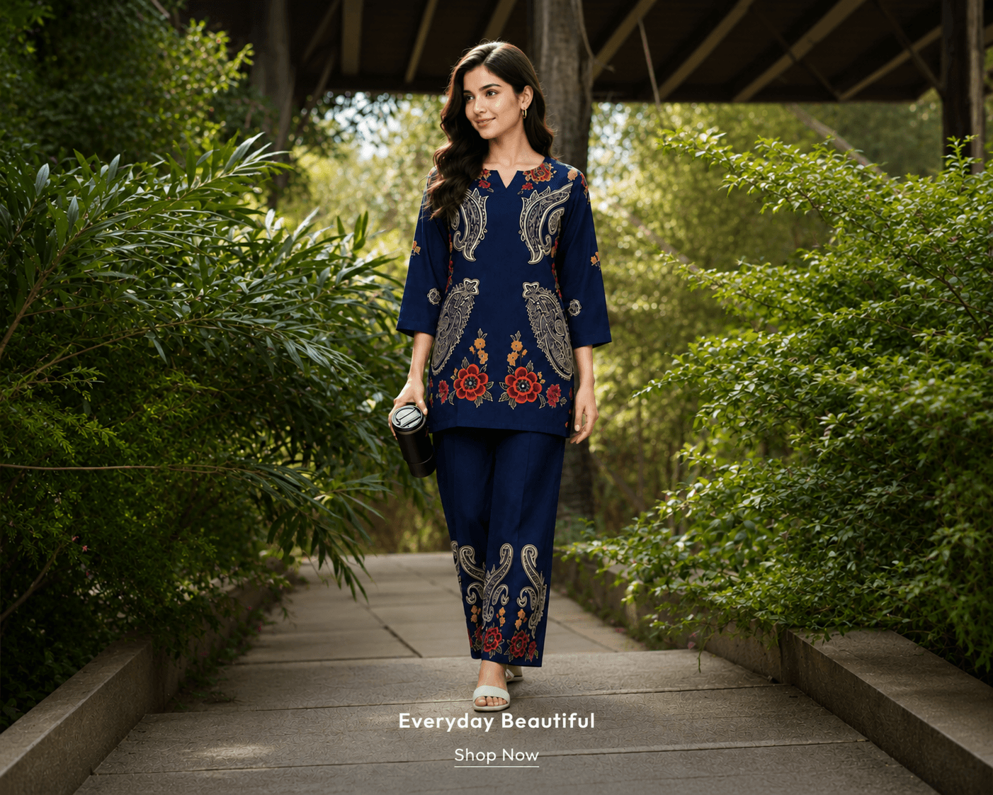 Model in a navy paisley co-ord walking through a garden